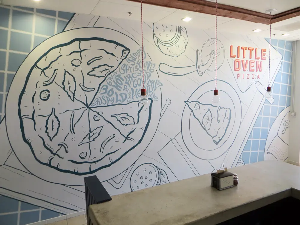 The hand-painted pizza mural and Little Oven Pizza sign on the shop wall
